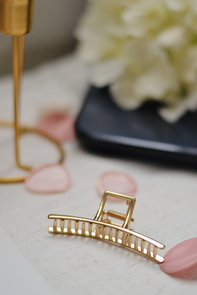 Luxury gold hair clip on soft beige linen background