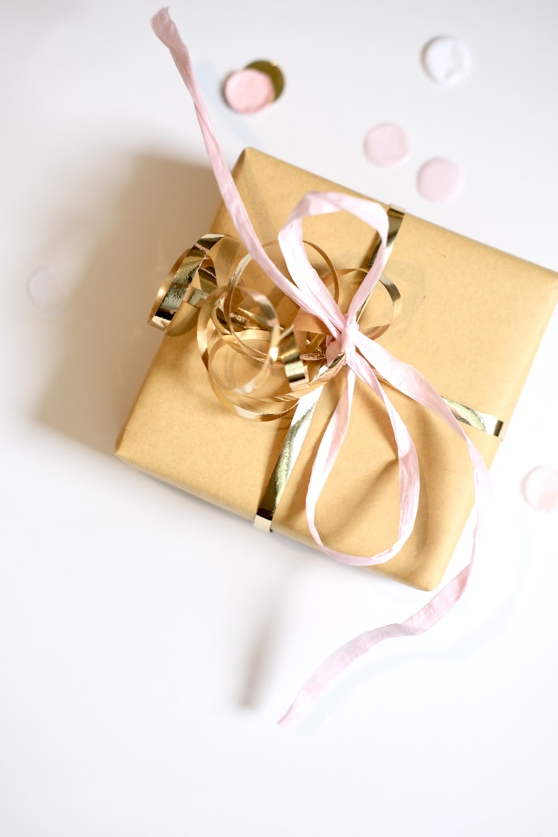 Elegant golden gift box with pink and gold ribbon on white background
